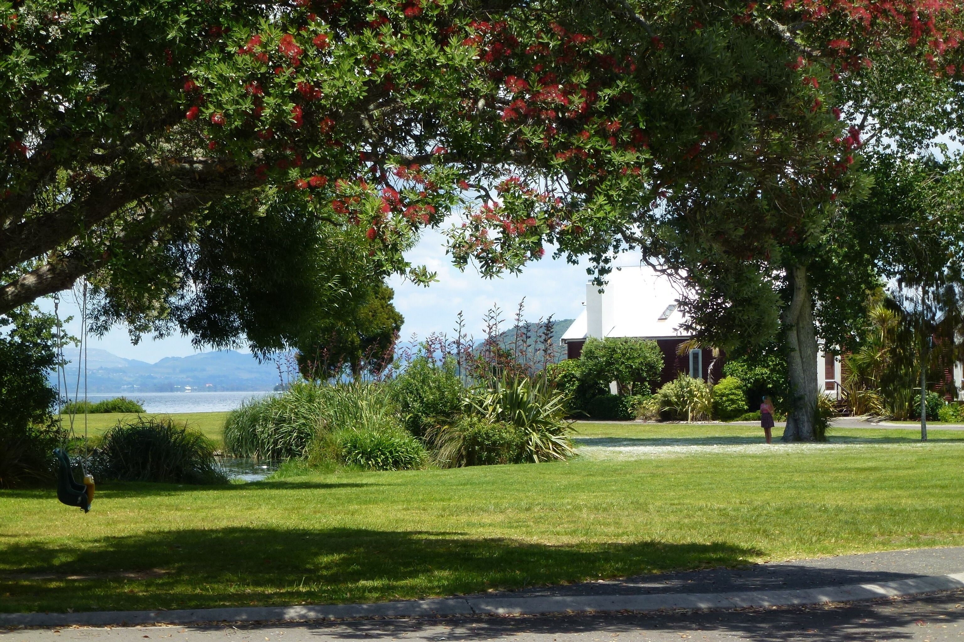 A park with a swing set, a grassy area, and a building in the background.