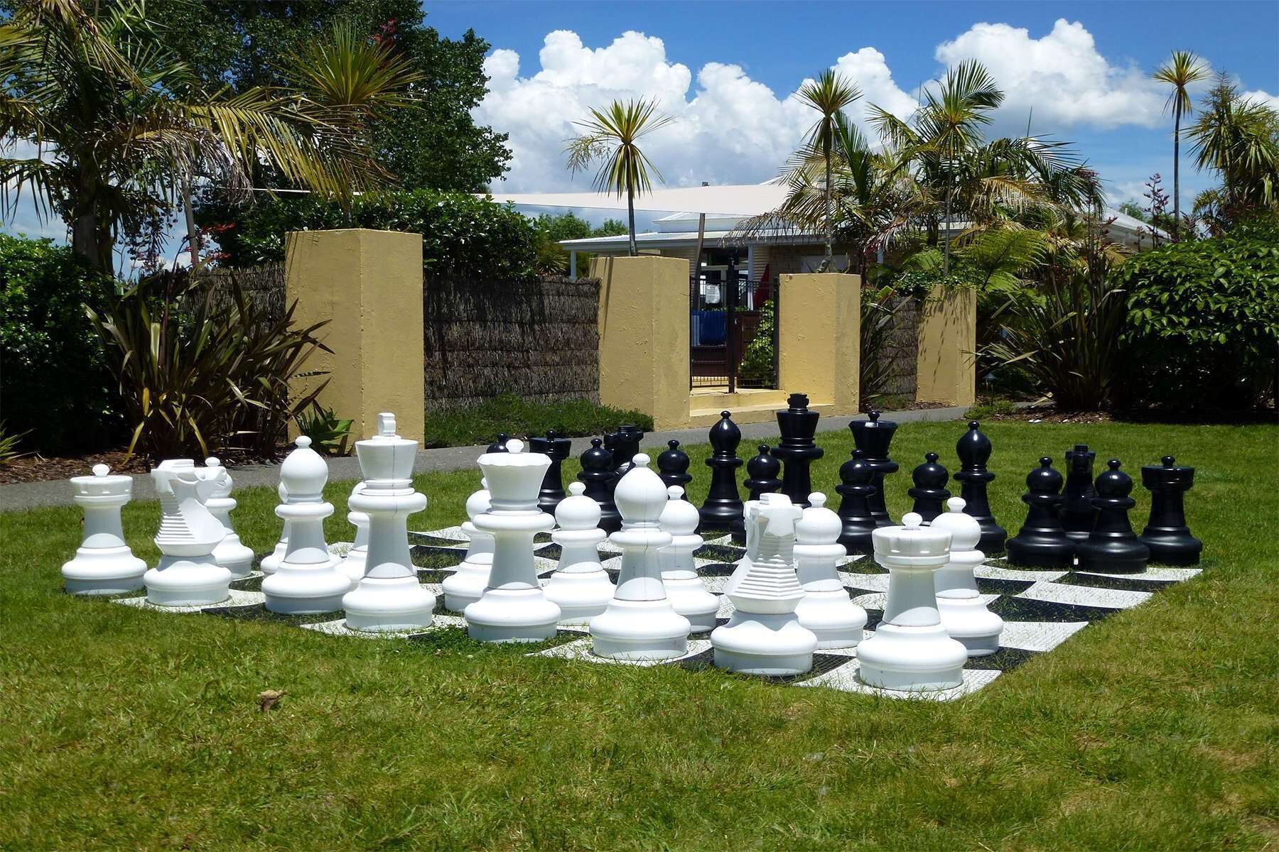 A chessboard set up outdoors with a building in the background.