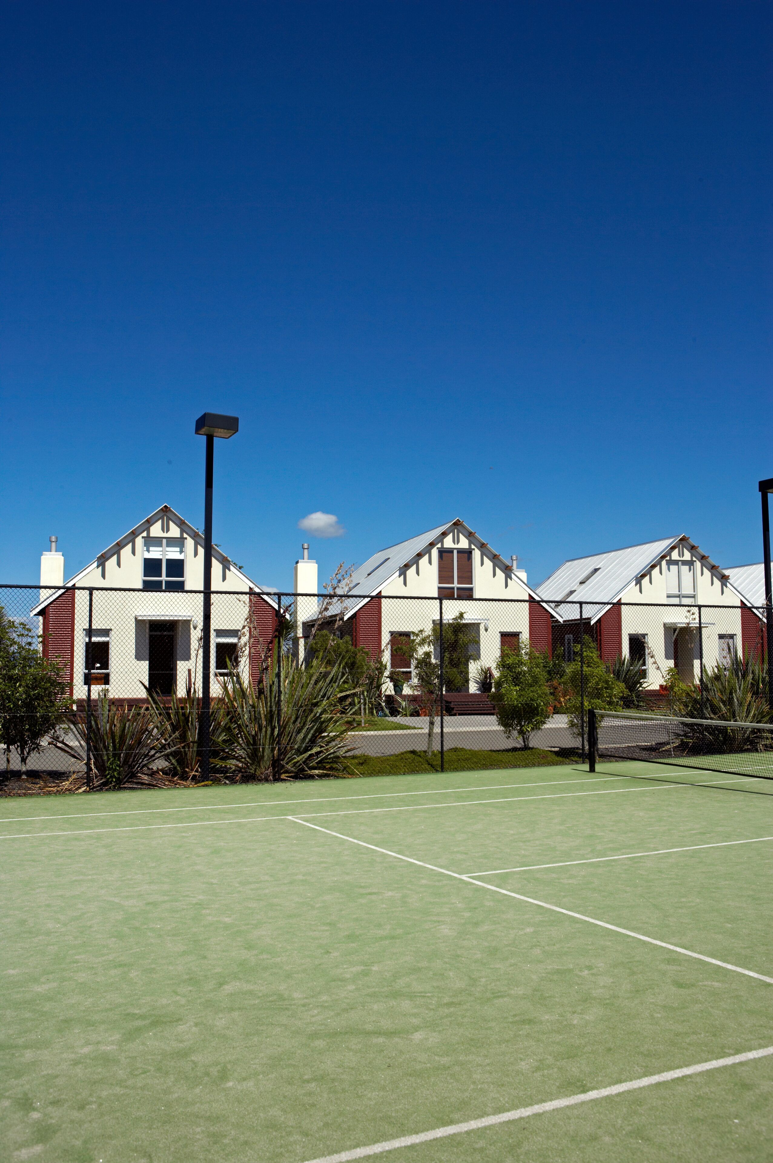 A row of three-story houses with a tennis court in front.