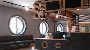 Un espace d’accueil moderne, doté d’un comptoir d’accueil sombre, de lambris en bois et de fenêtres rondes.