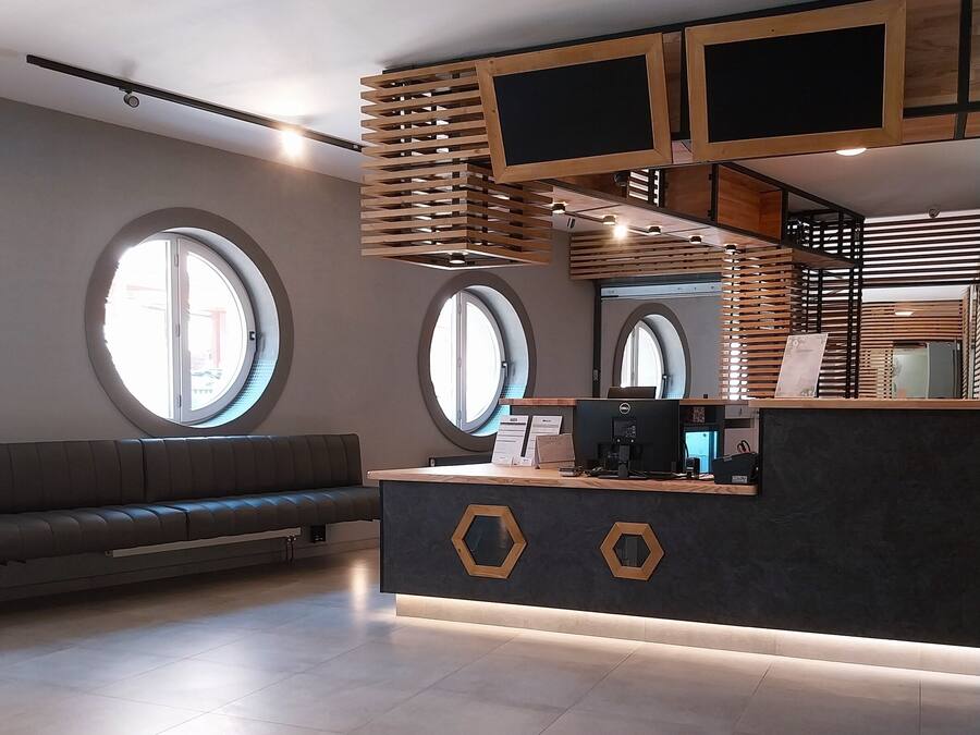 Un'area reception moderna con una scrivania scura, listelli di legno e finestre circolari.