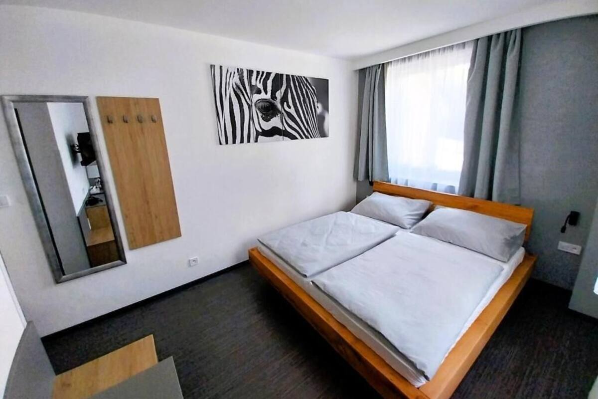 A modern hotel room with a wooden bed, a zebra print artwork, a mirror, and a wardrobe.