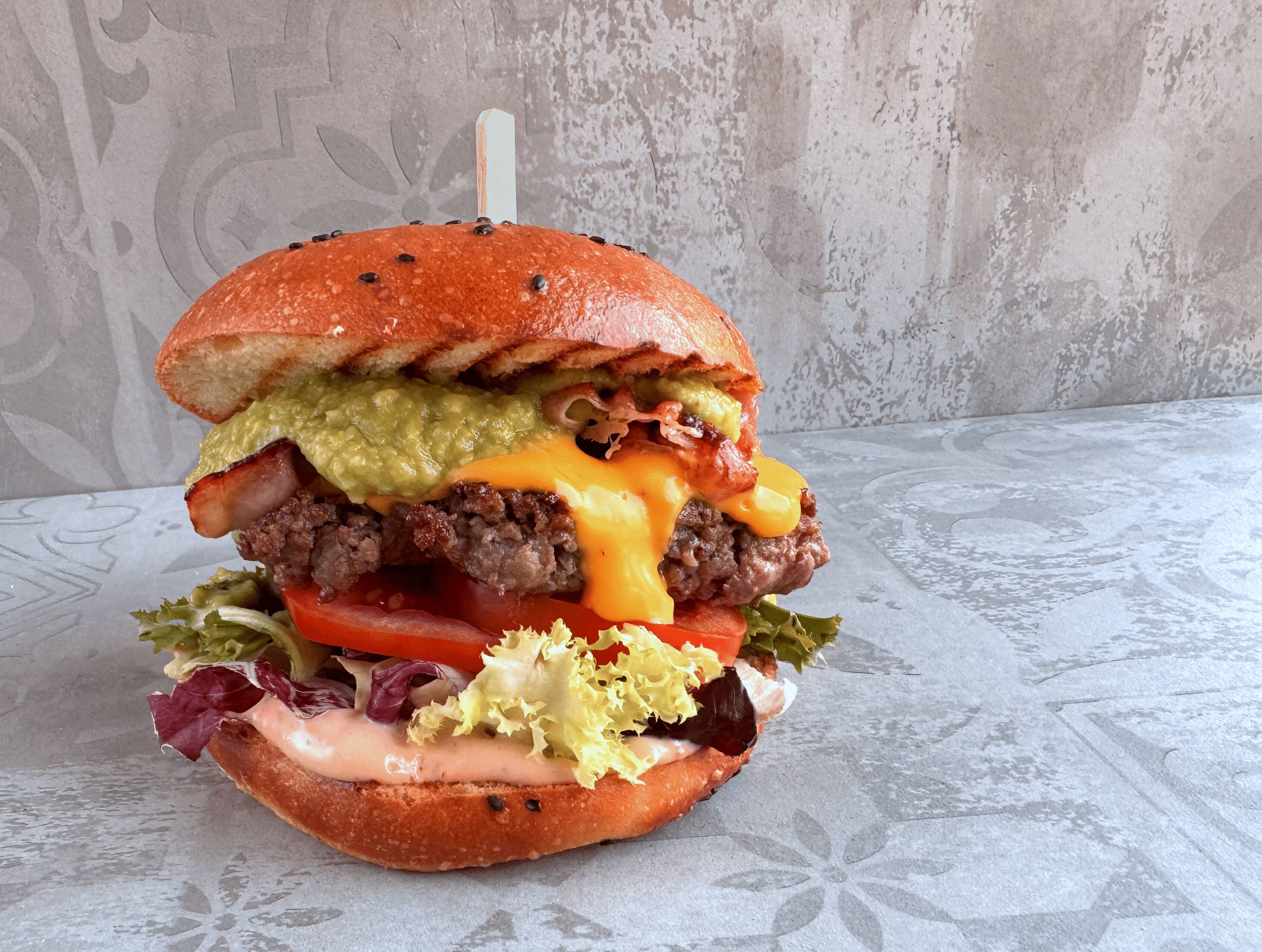 Een hamburger met sla, tomaat en kaas op een broodje.