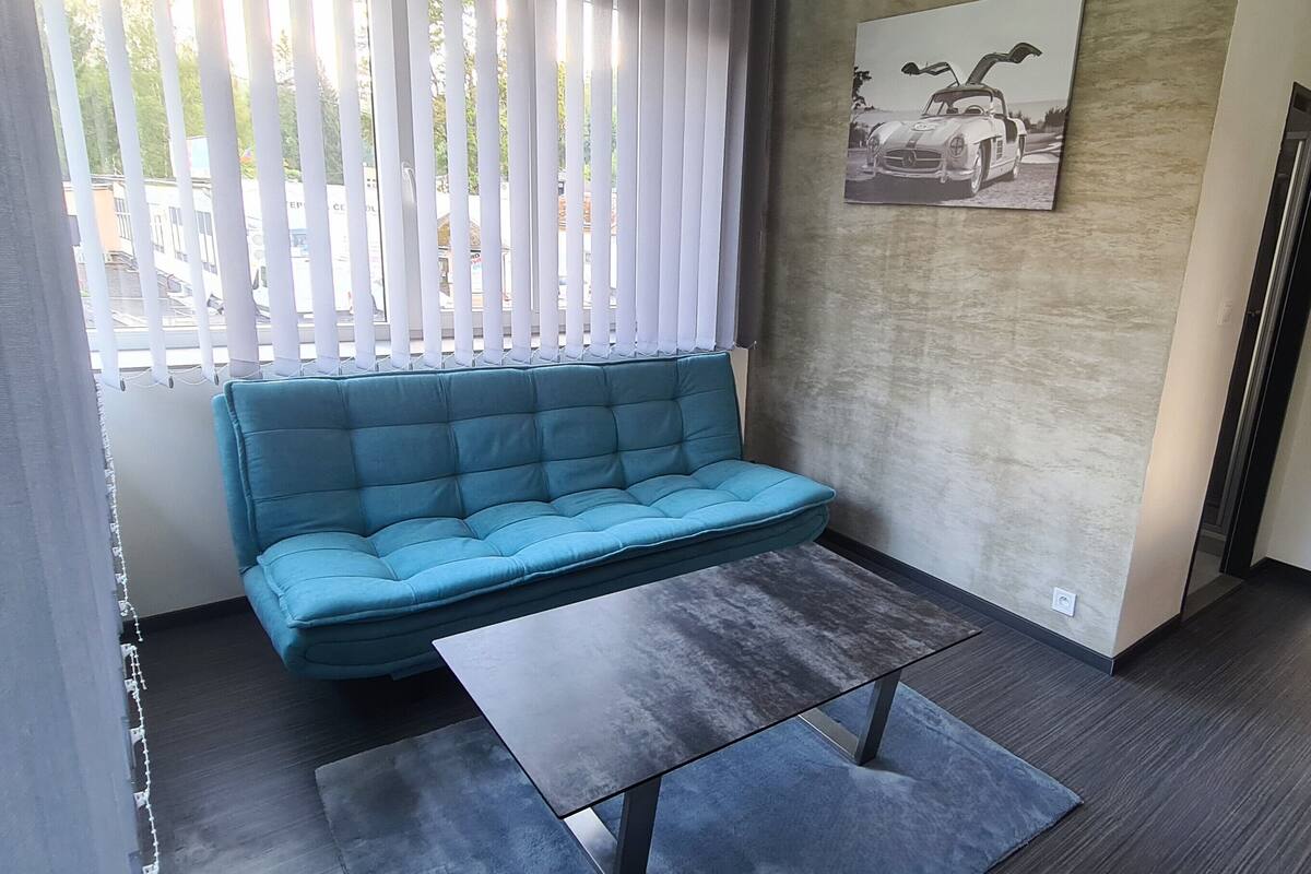 A modern living room with a blue sofa, a small table, and a framed picture on the wall.
