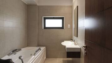 A modern bathroom with a bathtub, sink, and a window.