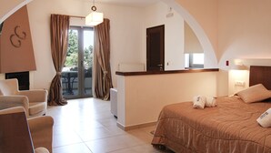A hotel room with a bed, a sitting area with a chair, a small table, and a view through a glass door to an outdoor area. - Delina Mountain Resort (Anogia)