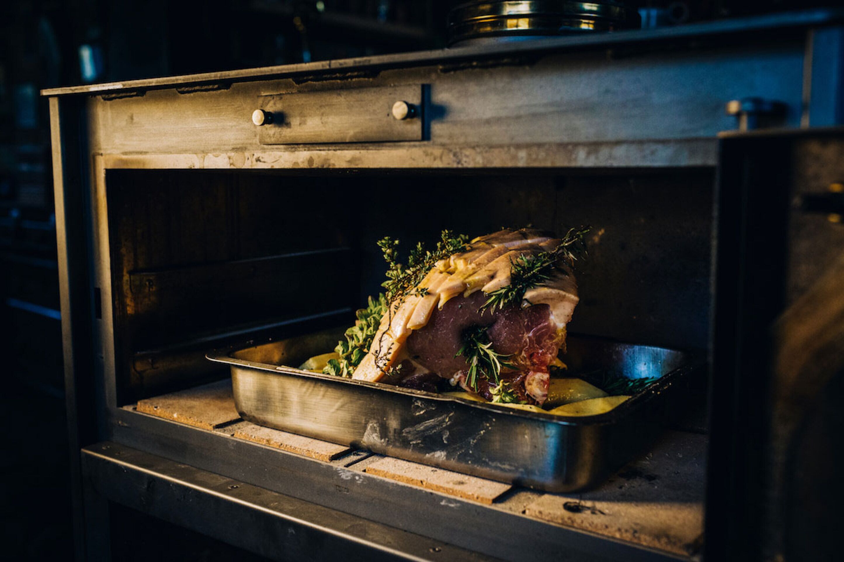 Un asado en el horno con una bandeja y hierbas.