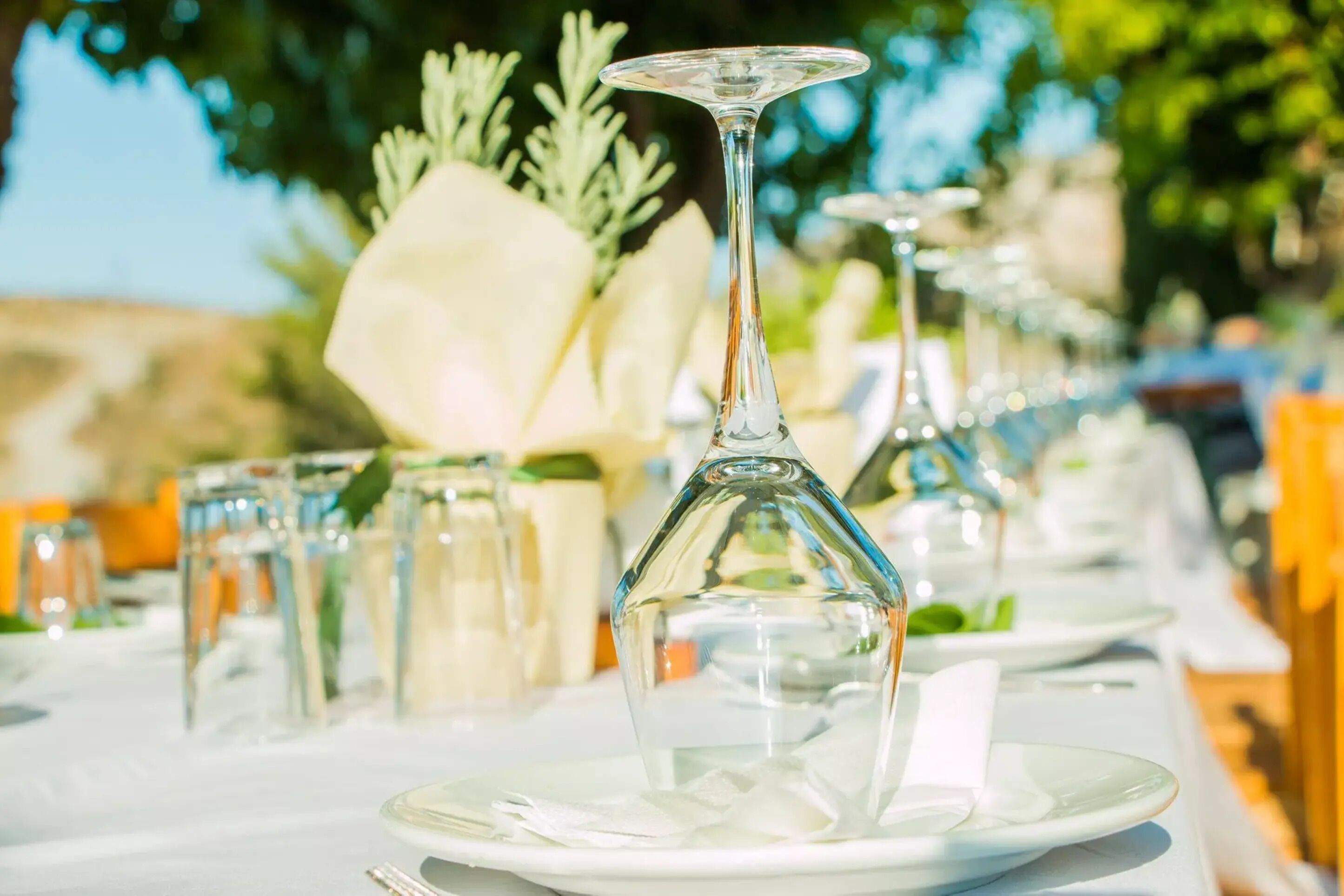 Une table à manger dressée avec de l’argenterie blanche, de la verrerie transparente et un centre de table composé de fleurs blanches.