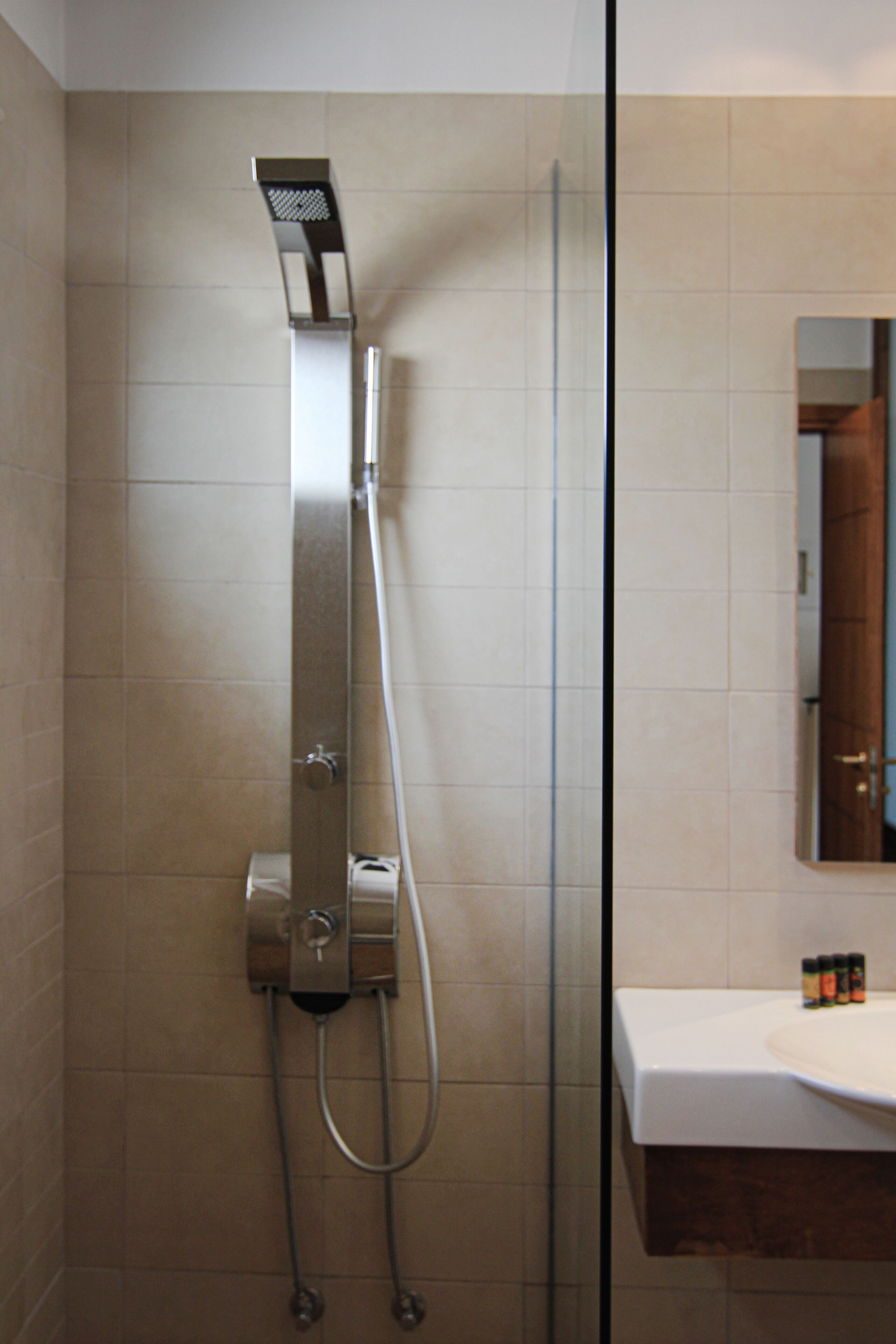 Un baño moderno con cabina de ducha de vidrio, un lavabo blanco y un espejo sobre él.