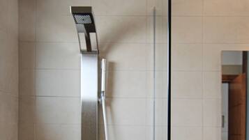 Un baño moderno con cabina de ducha de vidrio, un lavabo blanco y un espejo sobre él.