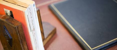 Una pila de libros sobre un atril de madera y un libro cerrado sobre una mesa.