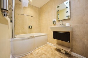 Un baño moderno con bañera, lavamanos y zona de ducha.