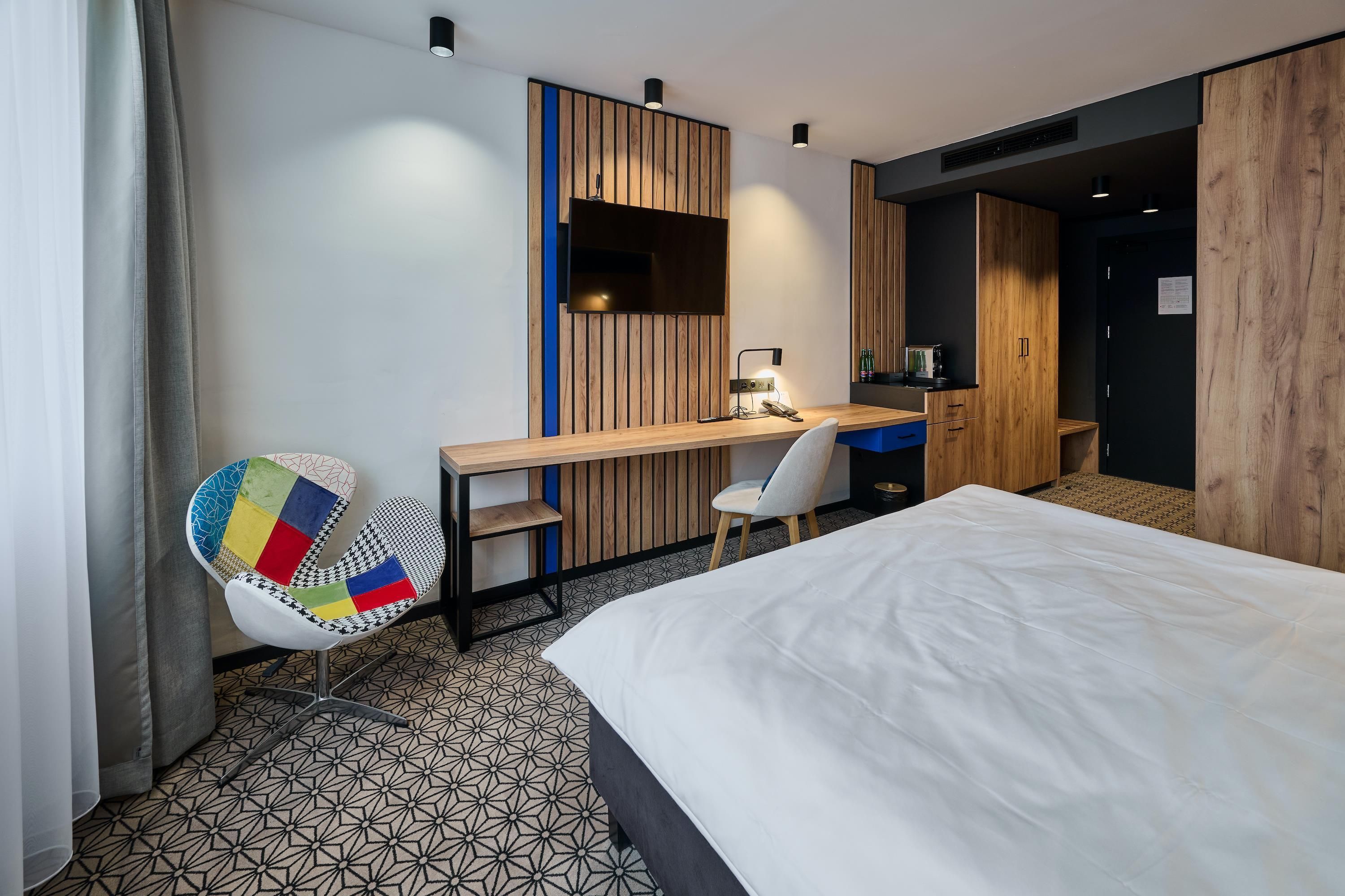 Una habitación de hotel con cama, escritorio, silla y armario.