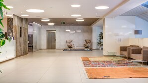 A modern lobby with a marble reception desk, two patterned chairs, a colorful rug, and a glass coffee table. - BEST WESTERN Hotel Vista (Ostrava)