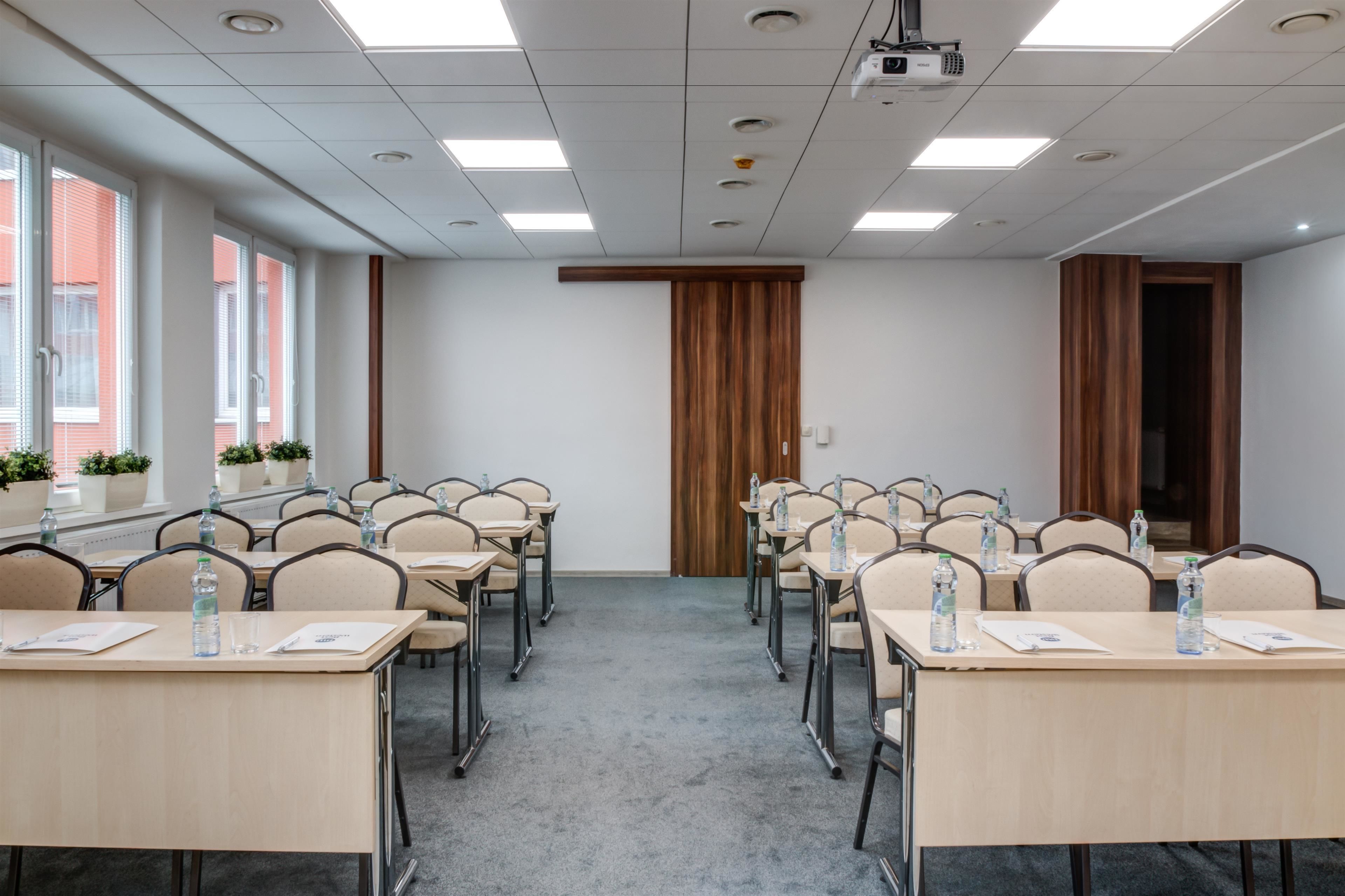 A conference room with multiple tables, chairs, and potted plants.