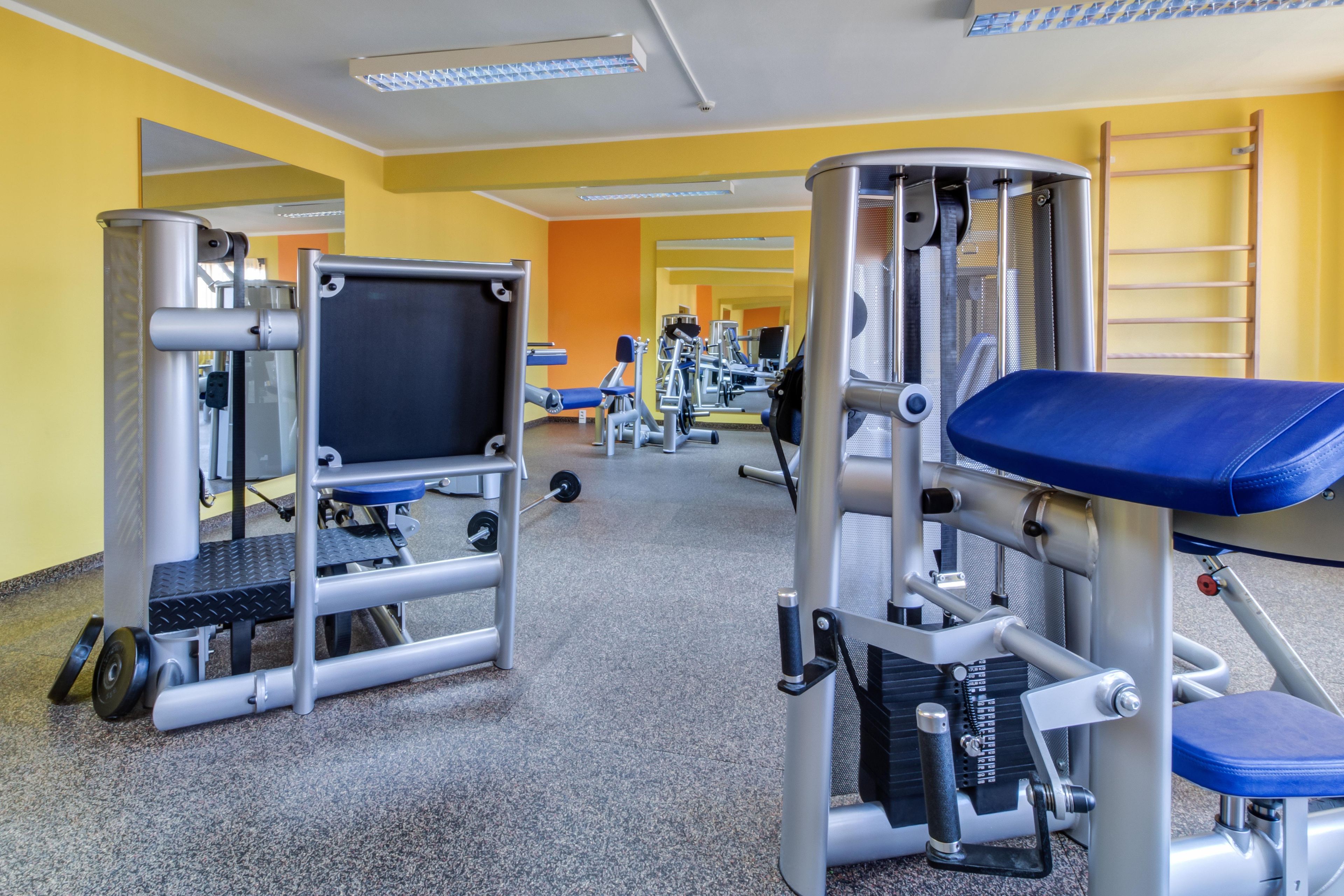 A gym with various exercise equipment, including weight machines and a bench.