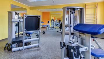 A gym with various exercise equipment, including weight machines and a bench.