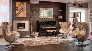 A modern hotel lobby with a grand piano, two unique armchairs, a fireplace, and a large abstract painting. - BEST WESTERN Hotel Vista (Ostrava)