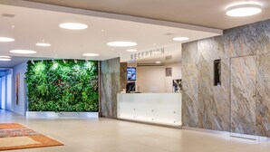 A modern reception area with a marble wall, a green plant wall, and a reception desk. - BEST WESTERN Hotel Vista (Ostrava)