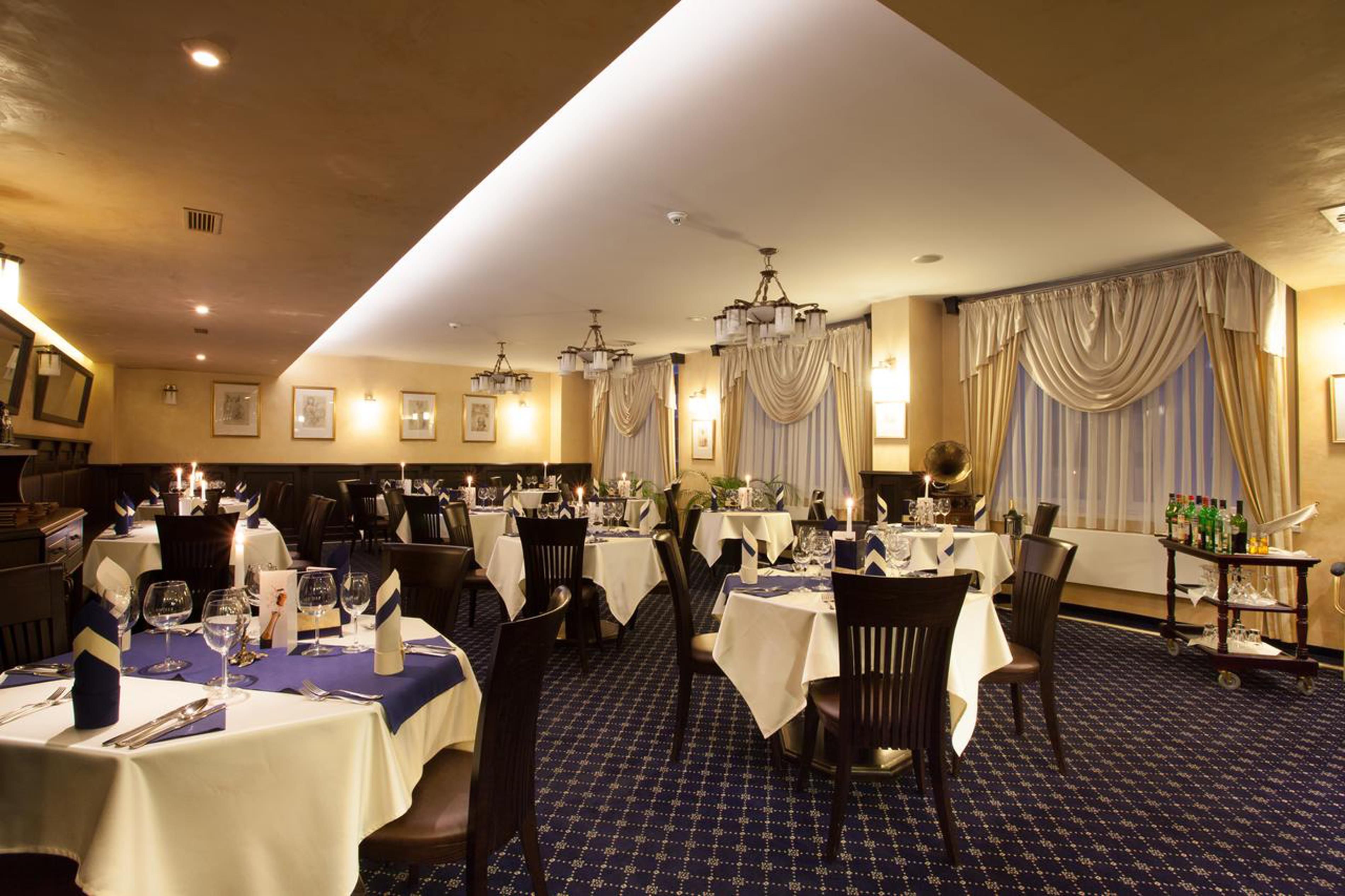 Un restaurante con varias mesas, candelabros y una alfombra estampada.
