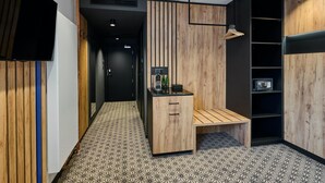A modern bathroom with a wooden vanity, a bench, and a shelf with a microwave. - BEST WESTERN Hotel Vista (Ostrava)