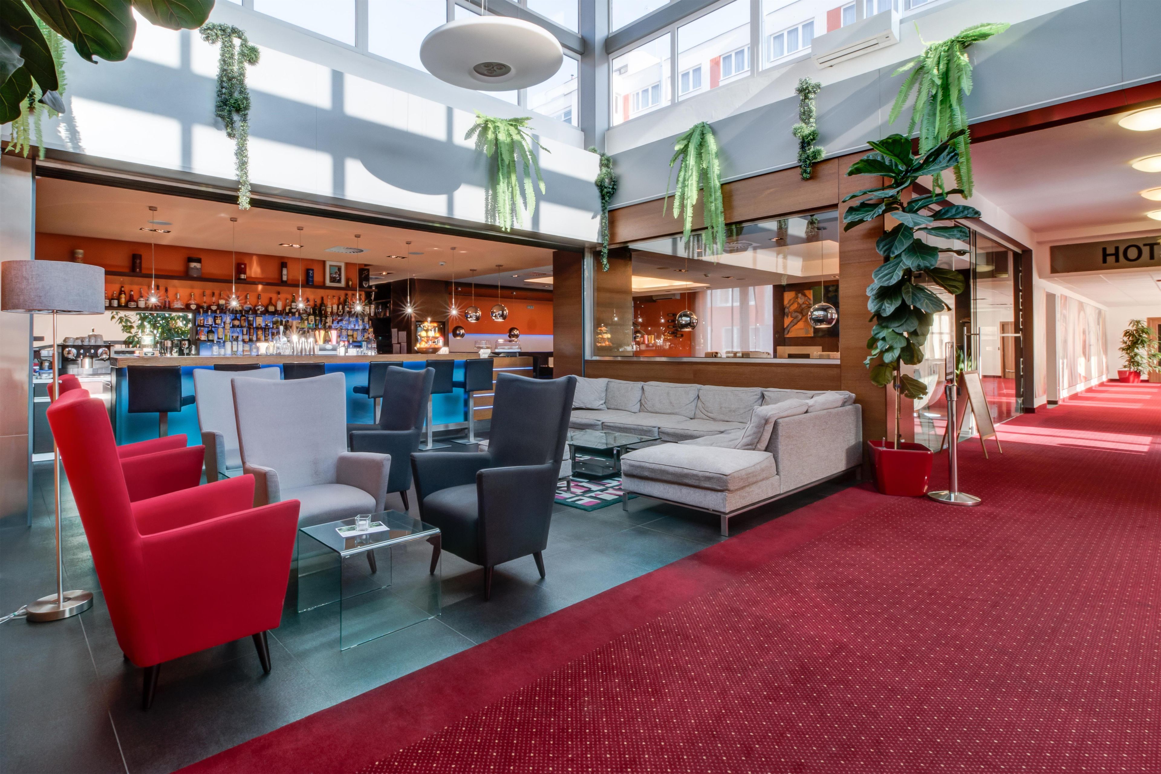 Eine Hotelhalle mit Sitzbereichen, einer Bar und einer Rezeption.
