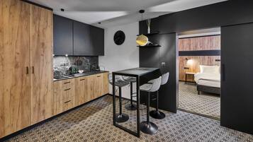 A compact kitchen with a marble countertop, wooden cabinets, and a bar area with stools.