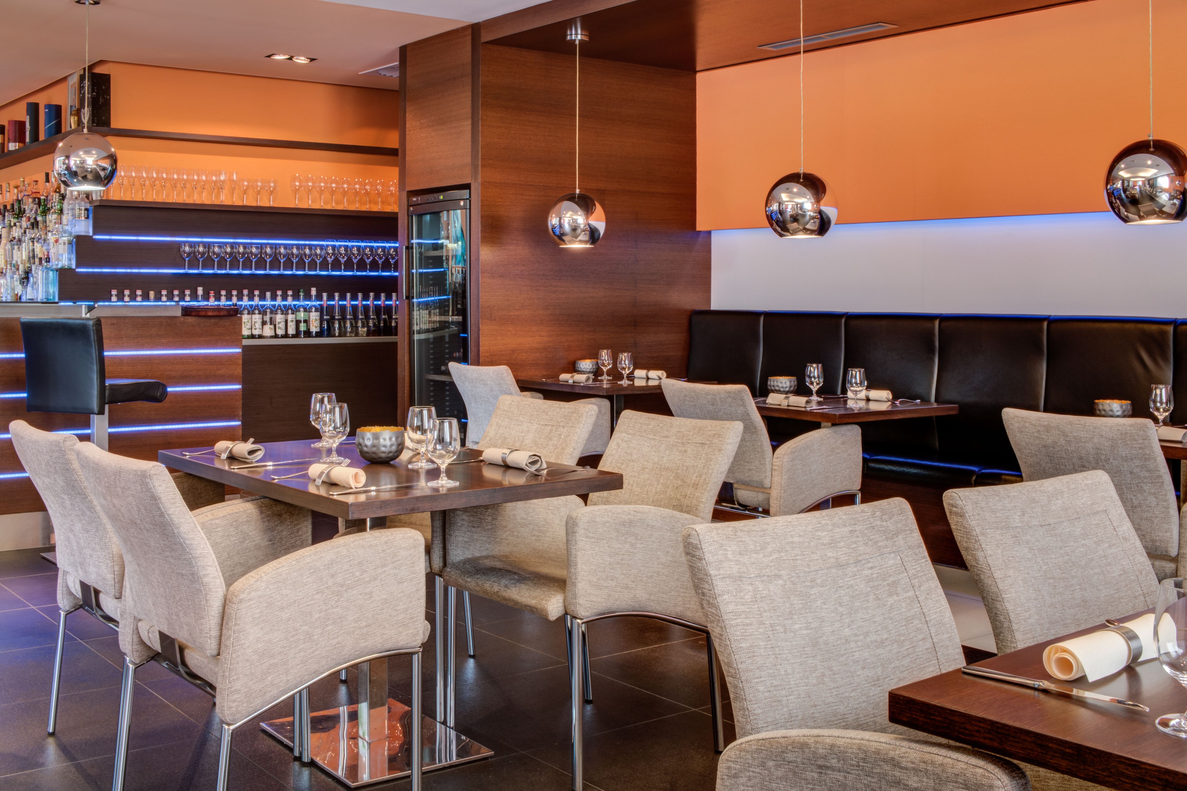 A modern restaurant with a bar area, multiple seating arrangements, and a well-stocked bar.