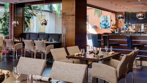 A modern restaurant with high tables and chairs, a bar area, and large windows with plants. - BEST WESTERN Hotel Vista (Ostrava)