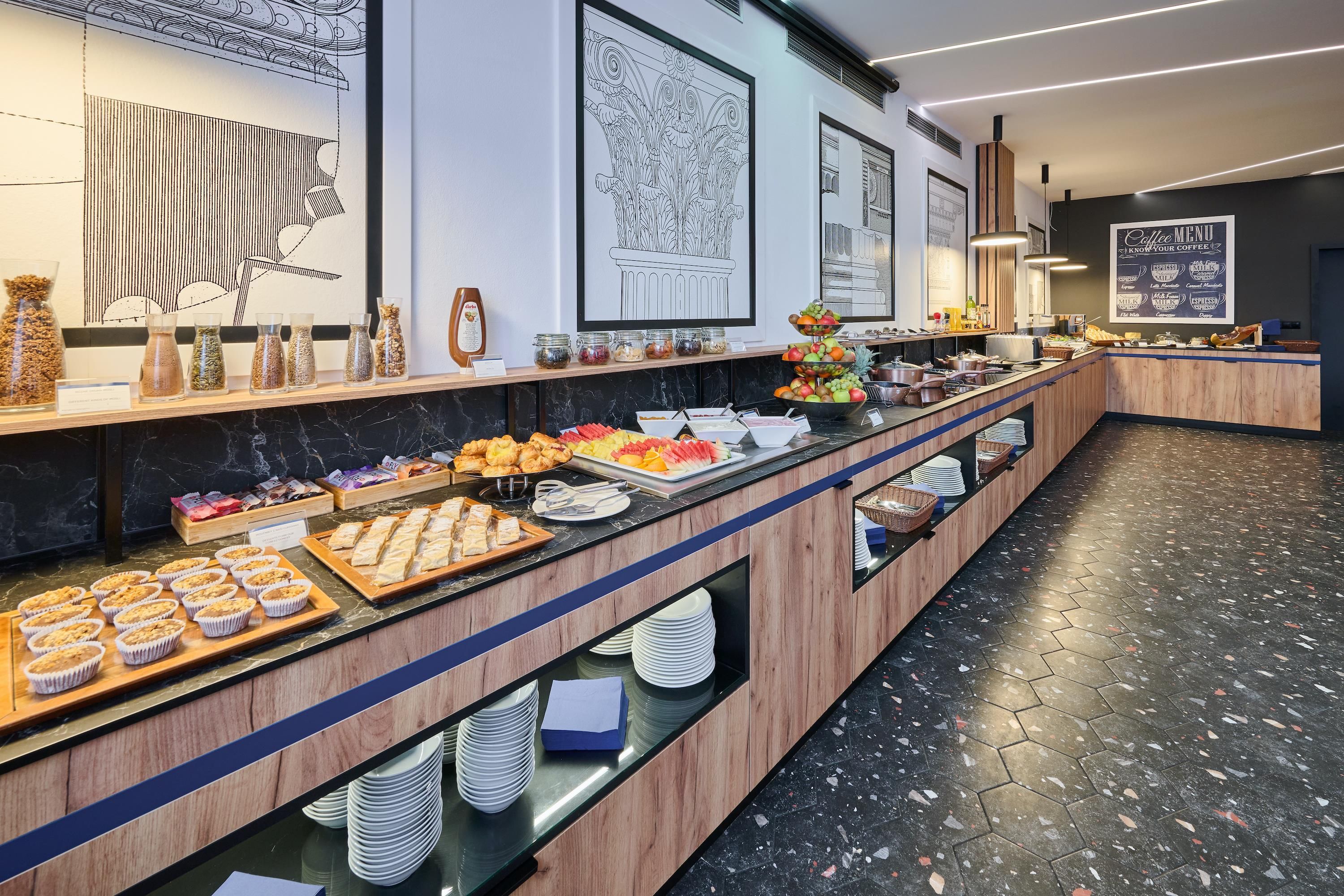 A buffet with various food items, a coffee menu, and decorative wall art.