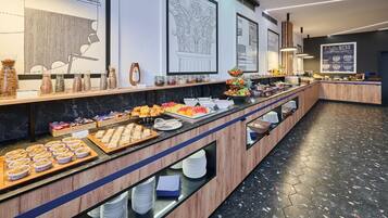A buffet with various food items, a coffee menu, and decorative wall art.