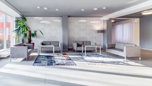 A modern living room with grey sofas, a coffee table, and a large plant. - BEST WESTERN Hotel Vista (Ostrava)