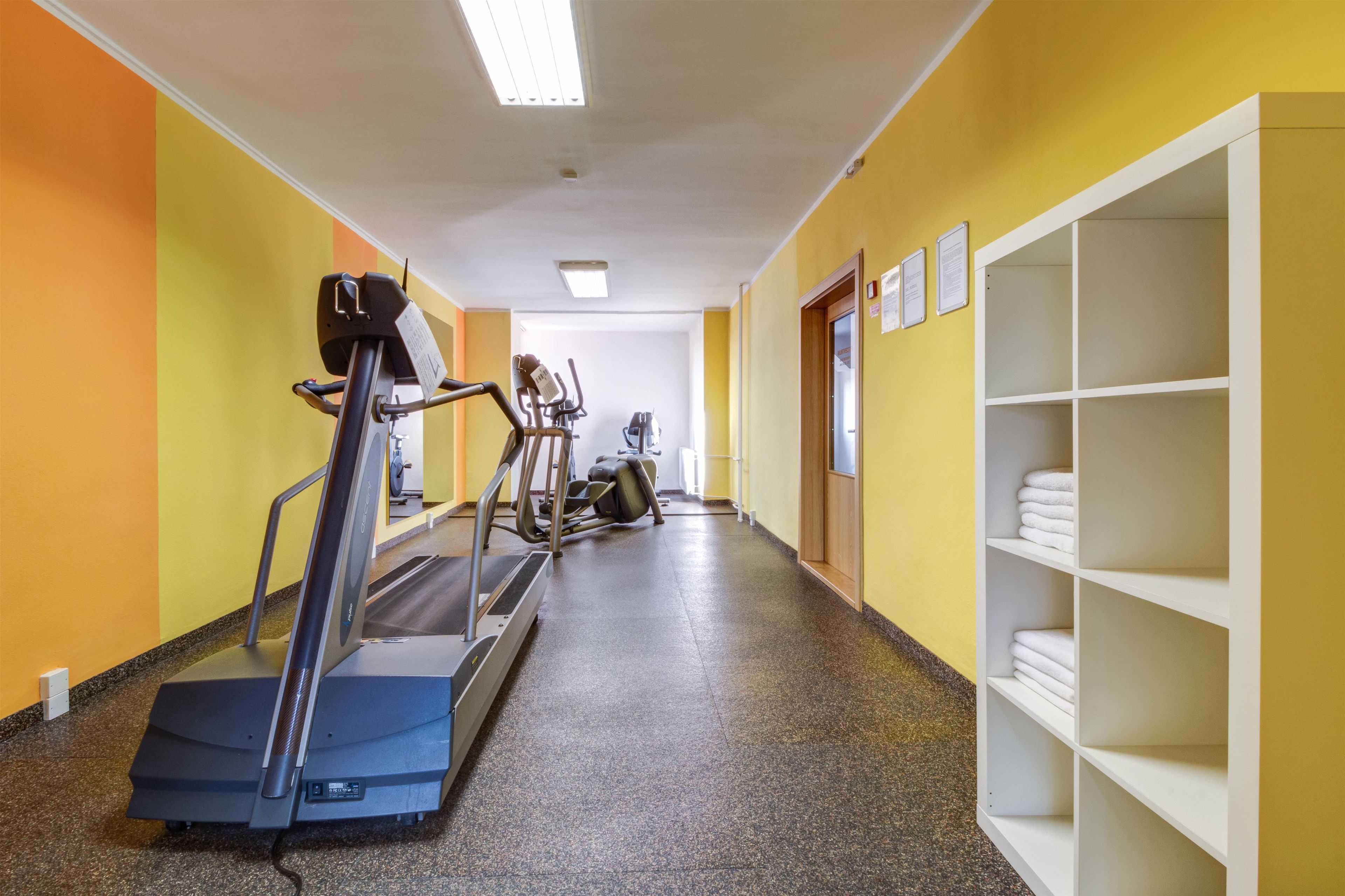 A gym with treadmills, stationary bikes, and a wall-mounted rack with towels.