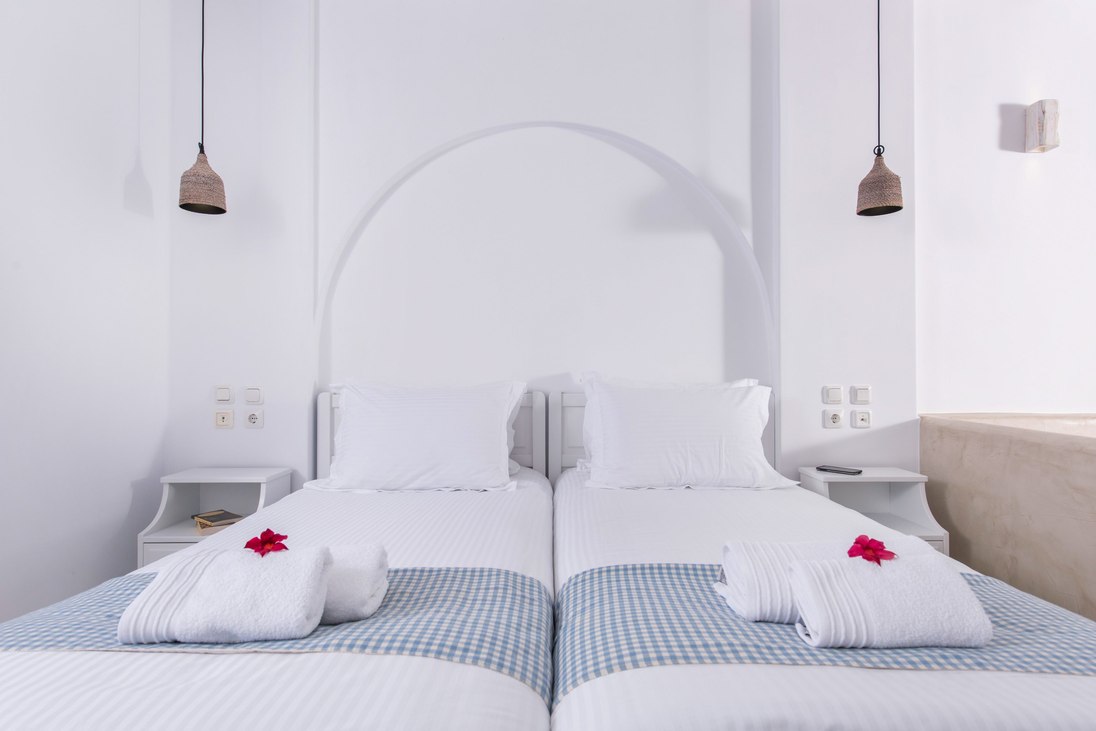 Habitación de hotel con dos camas, ropa blanca y un amplio ventanal en arco.