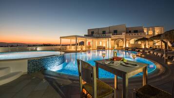 Een buitenzwembad, ligstoelen bij het zwembad