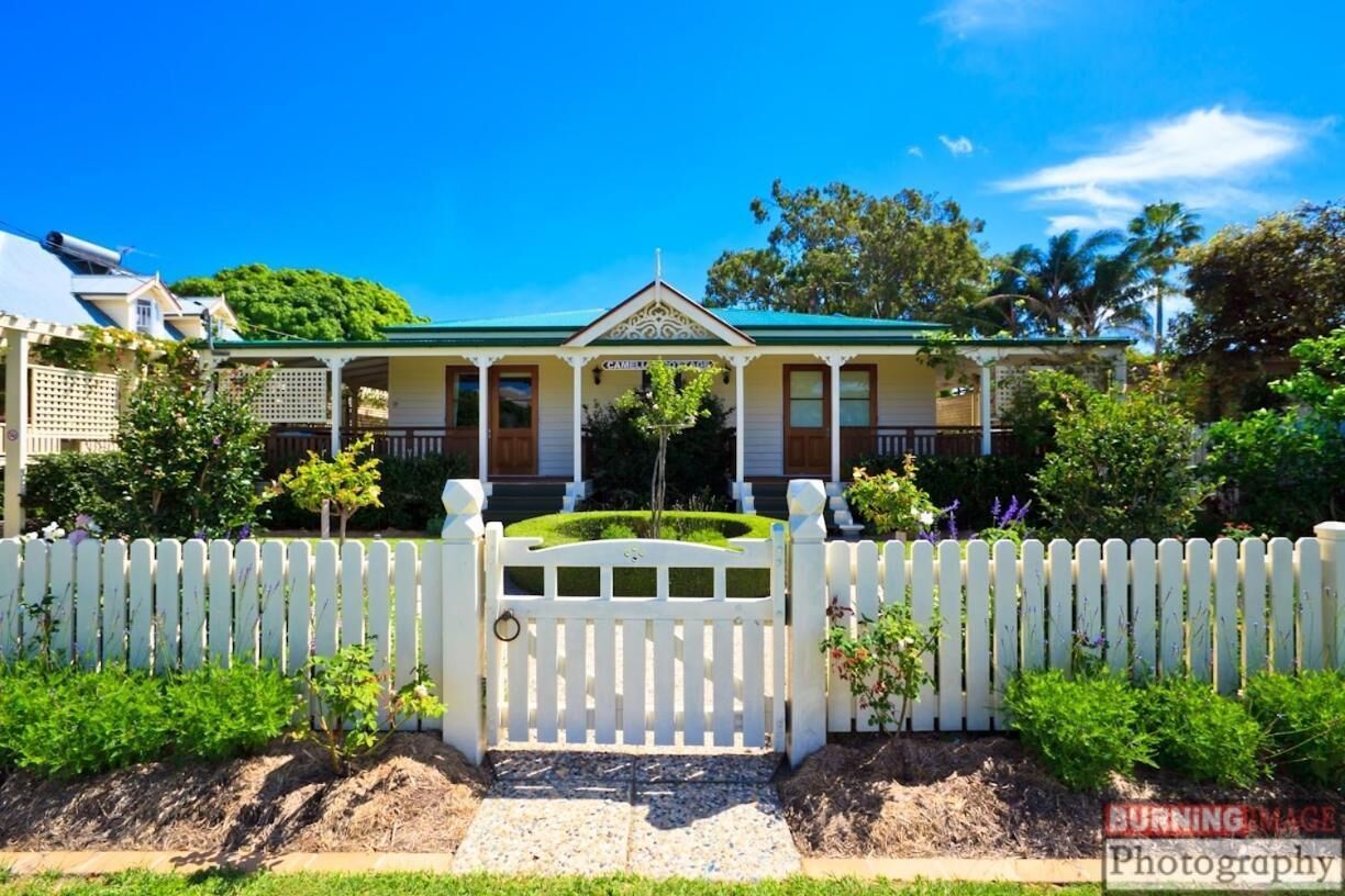 A house with a white picket fence, a front porch, and a well-maintained garden.