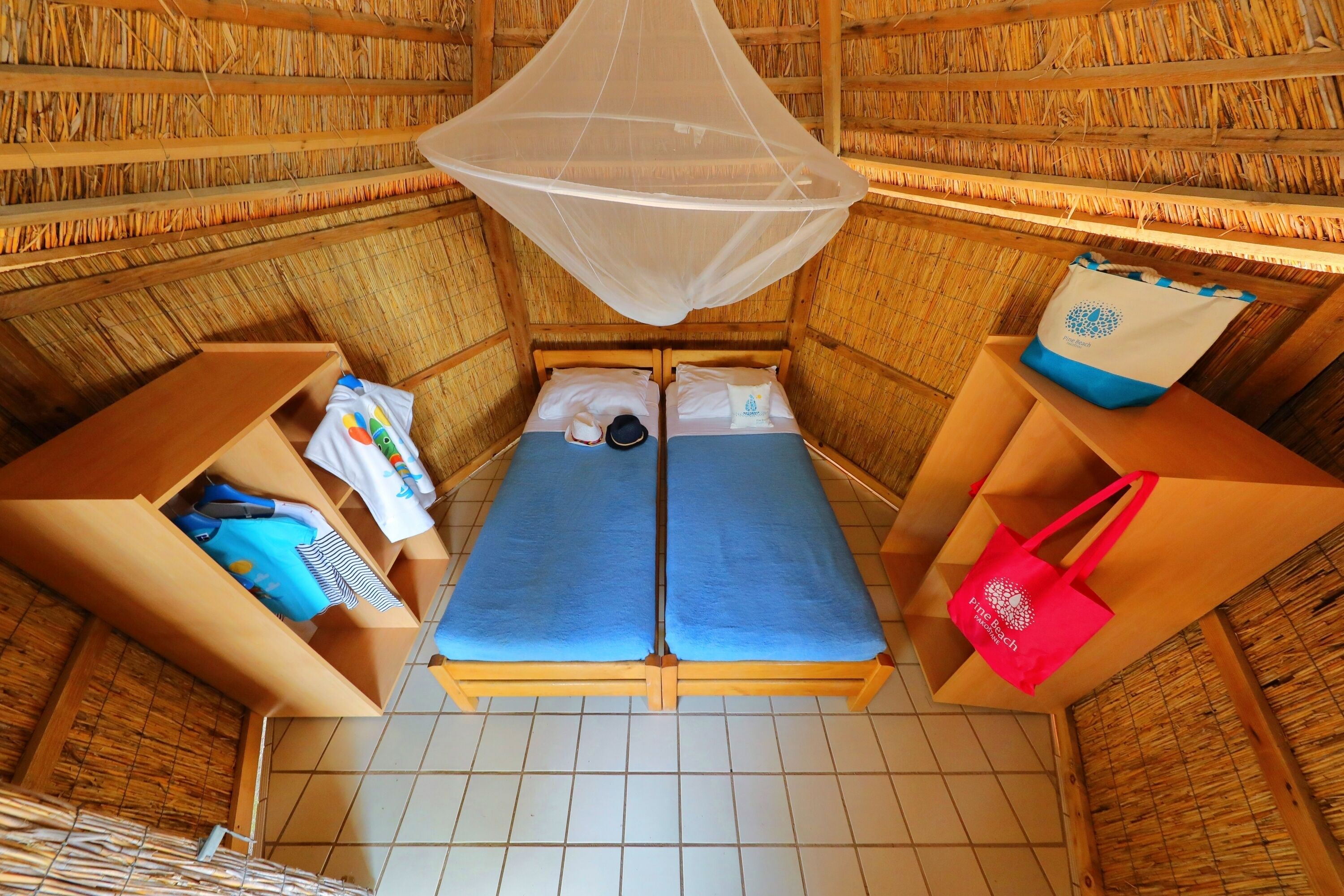 Une chambre avec un lit, une moustiquaire et une petite table sur laquelle se trouve un sac.