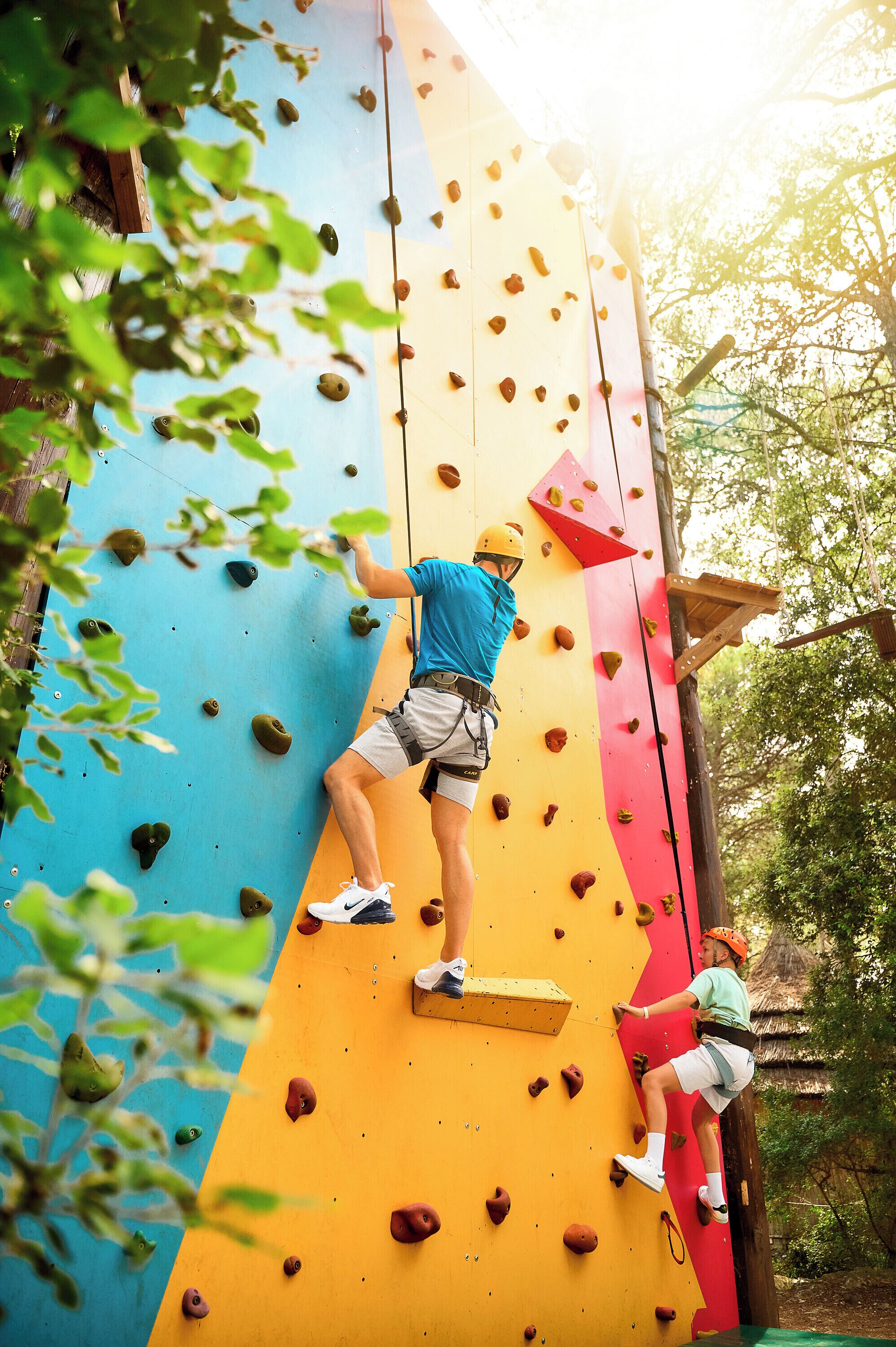 A person climbing a colorful artificial rock wall with various holds.