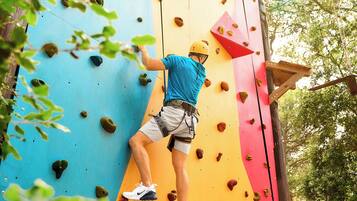 A person climbing a colorful artificial rock wall with various holds.