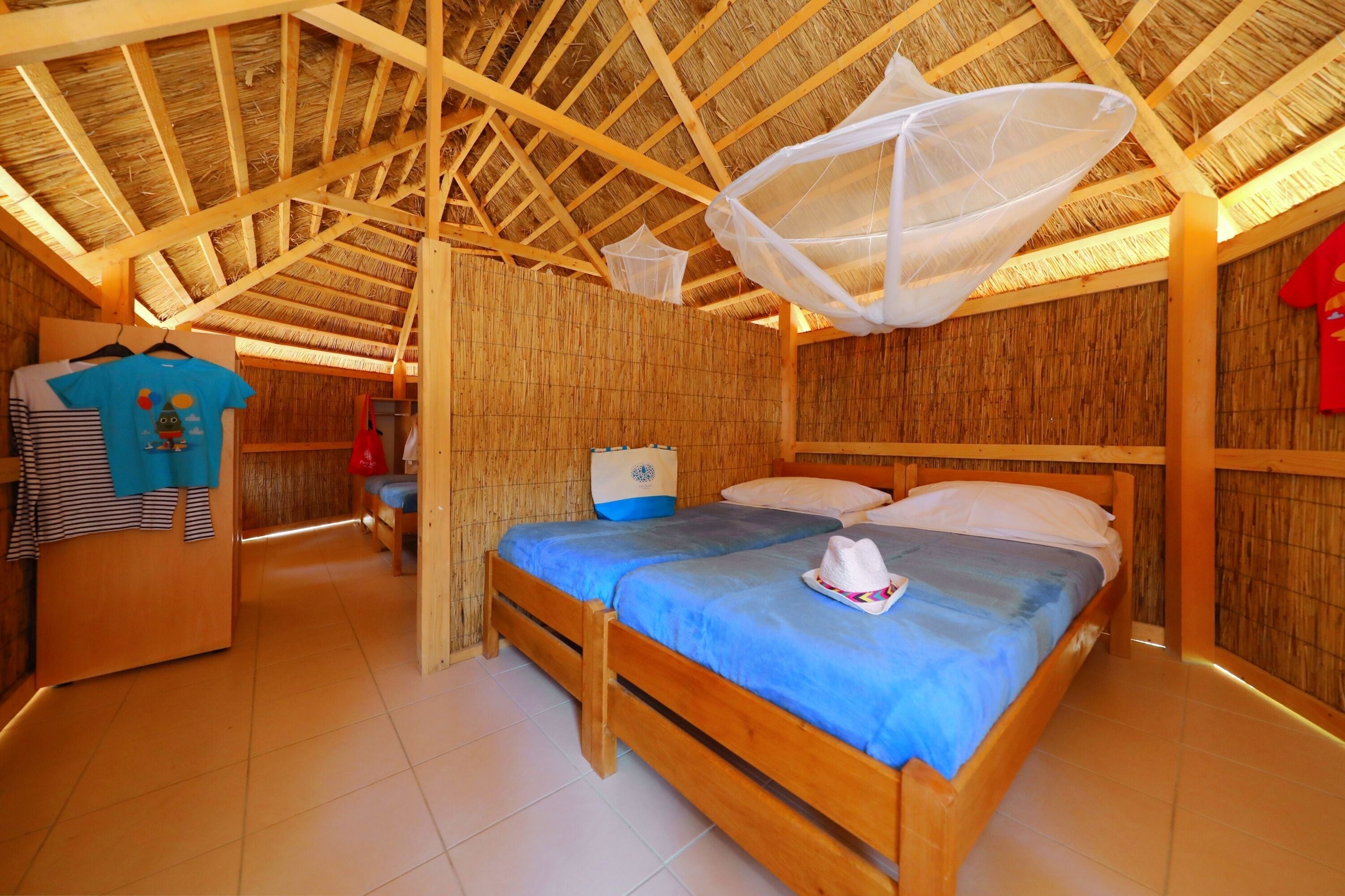 A room with a wooden bed, a wardrobe, and a hanging mosquito net.
