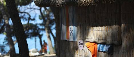 Una cabaña rústica con techo de paja, un cartel con número e una bandera.