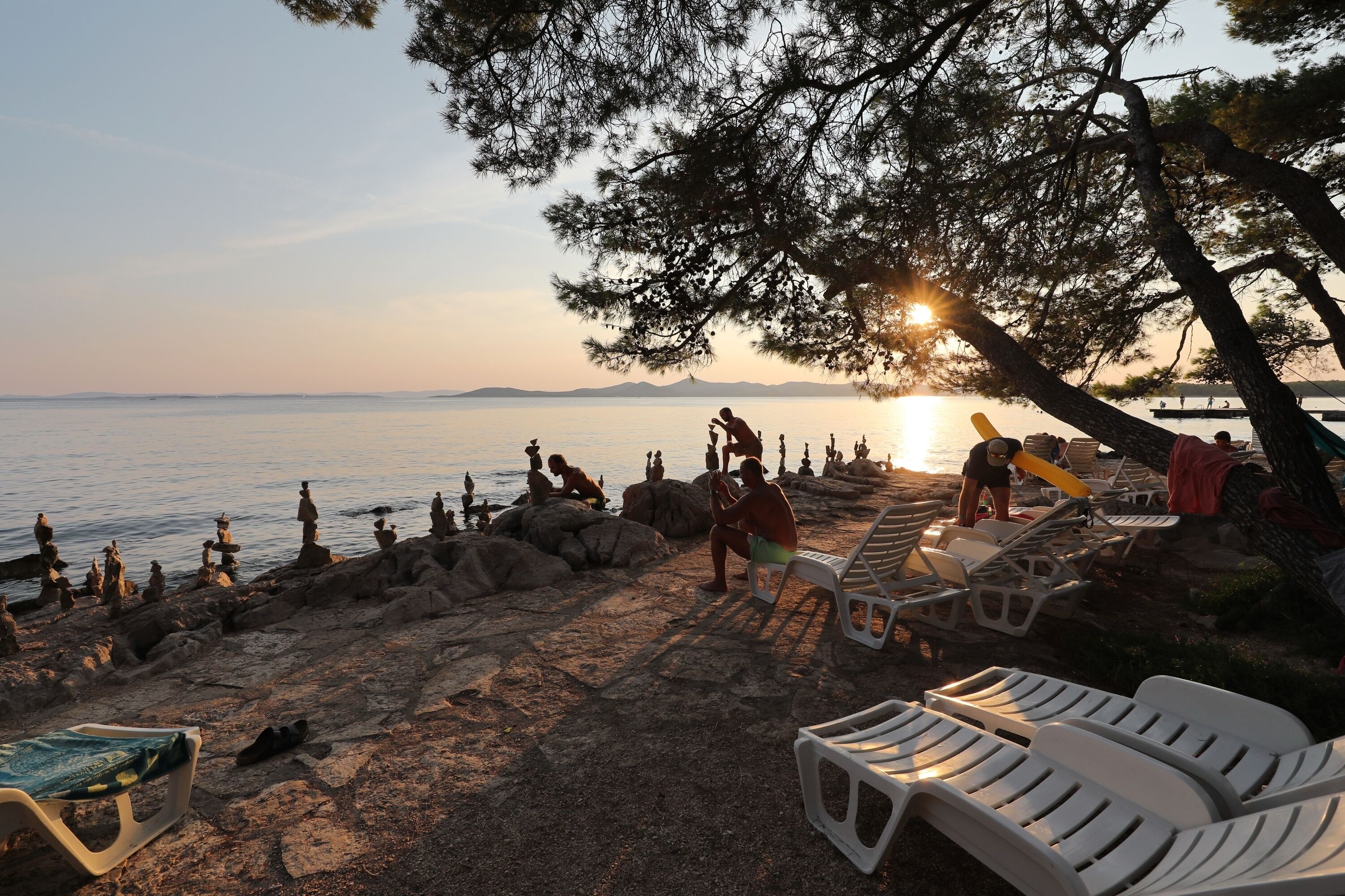 Une plage avec des chaises longues et des gens qui se détendent.
