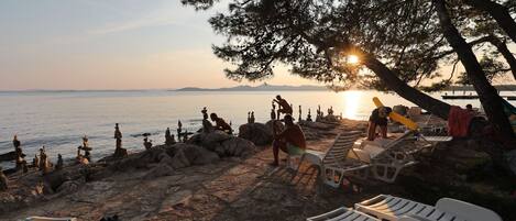 A beach with lounge chairs and people relaxing.