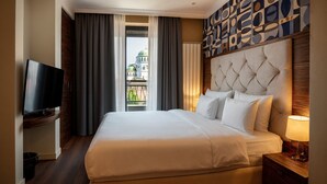 Habitación de hotel con una cama grande, un televisor sobre un soporte de madera, vista de un edificio a través de la ventana y una pared con diseño.