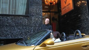 Un coche descapotable amarillo estacionado frente a un edificio con un letrero que dice "GRAND HOTEL".