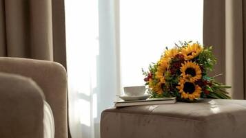 Una habitación con un sofá, una mesa con un jarrón de girasoles y una ventana con cortinas.