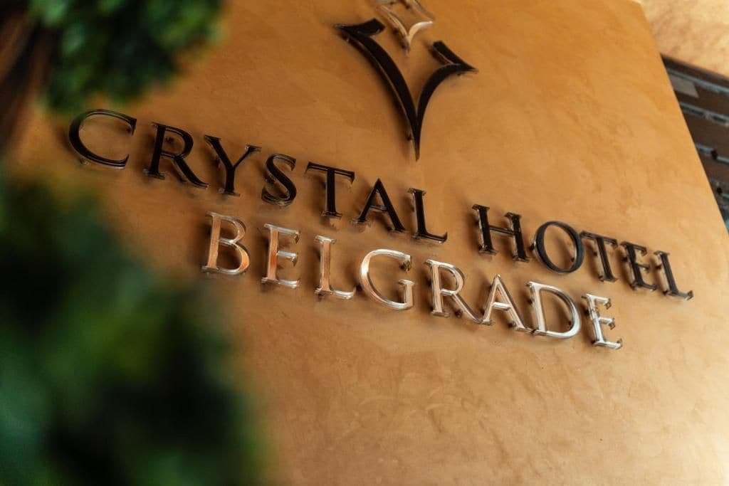 Schild für das Crystal Hotel Belgrad mit einem stilisierten 'V'-Logo über dem Text.