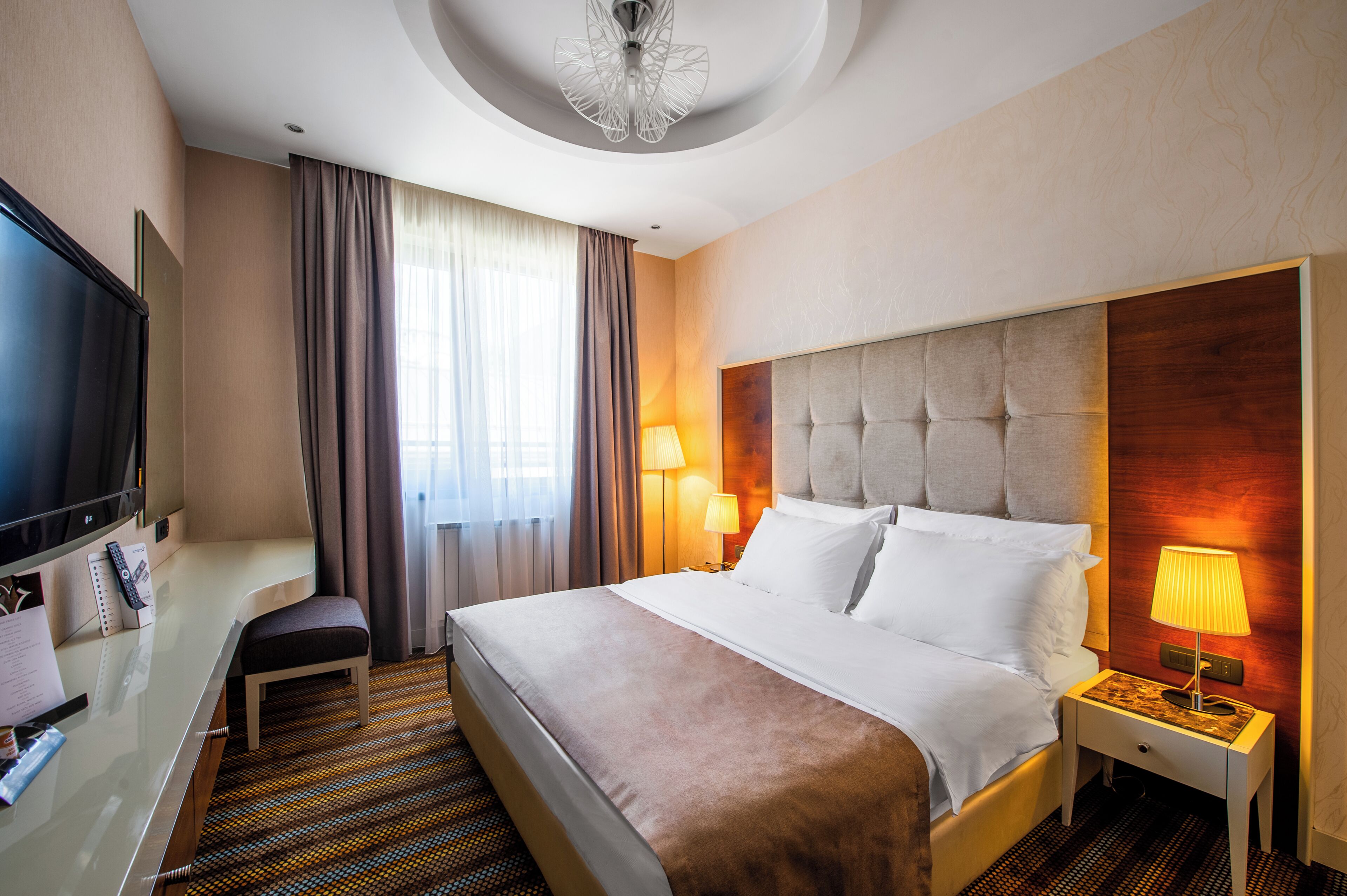 Habitación de hotel con una cama grande, televisor, escritorio y una silla.