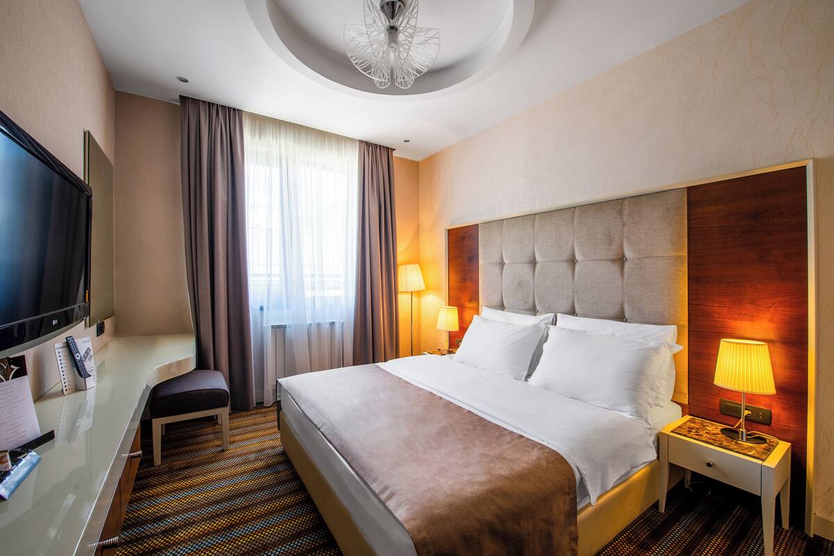 Habitación de hotel con una cama grande, televisor, escritorio y una silla.