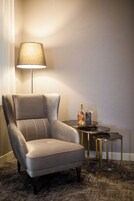 A modern armchair with a lamp and a small table with a bottle and glasses.